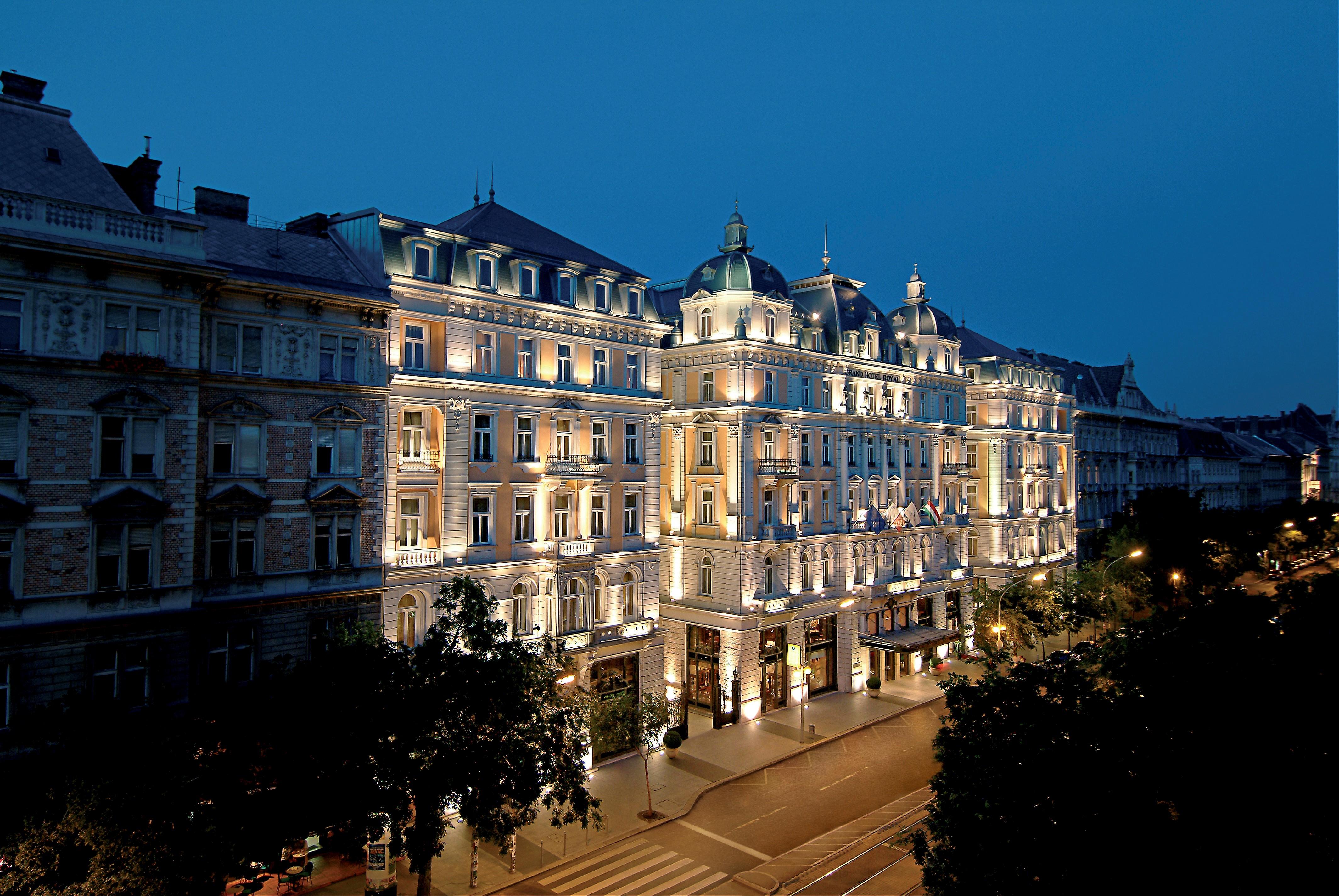 Corinthia Budapest Eksteriør billede The photo shows a beautifully illuminated historic building at night. The architecture features elegant details, including ornamental facades and a prominent roof structure, typical of classic European design. The building is lit up, highlighting its